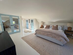 A bedroom with a large bed, a desk, and a wardrobe with mirrored doors. - Designer renovated 4-bedroom house in coveted Bonnet Shores with AC (Narragansett)