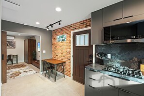 Una cocina moderna con estufa a gas, electrodomésticos de acero inoxidable y una pared decorativa de ladrillo.