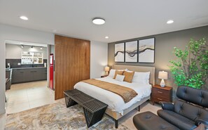 Una habitación de hotel moderna con una cama grande, mesitas de noche, un escritorio y un área de descanso.
