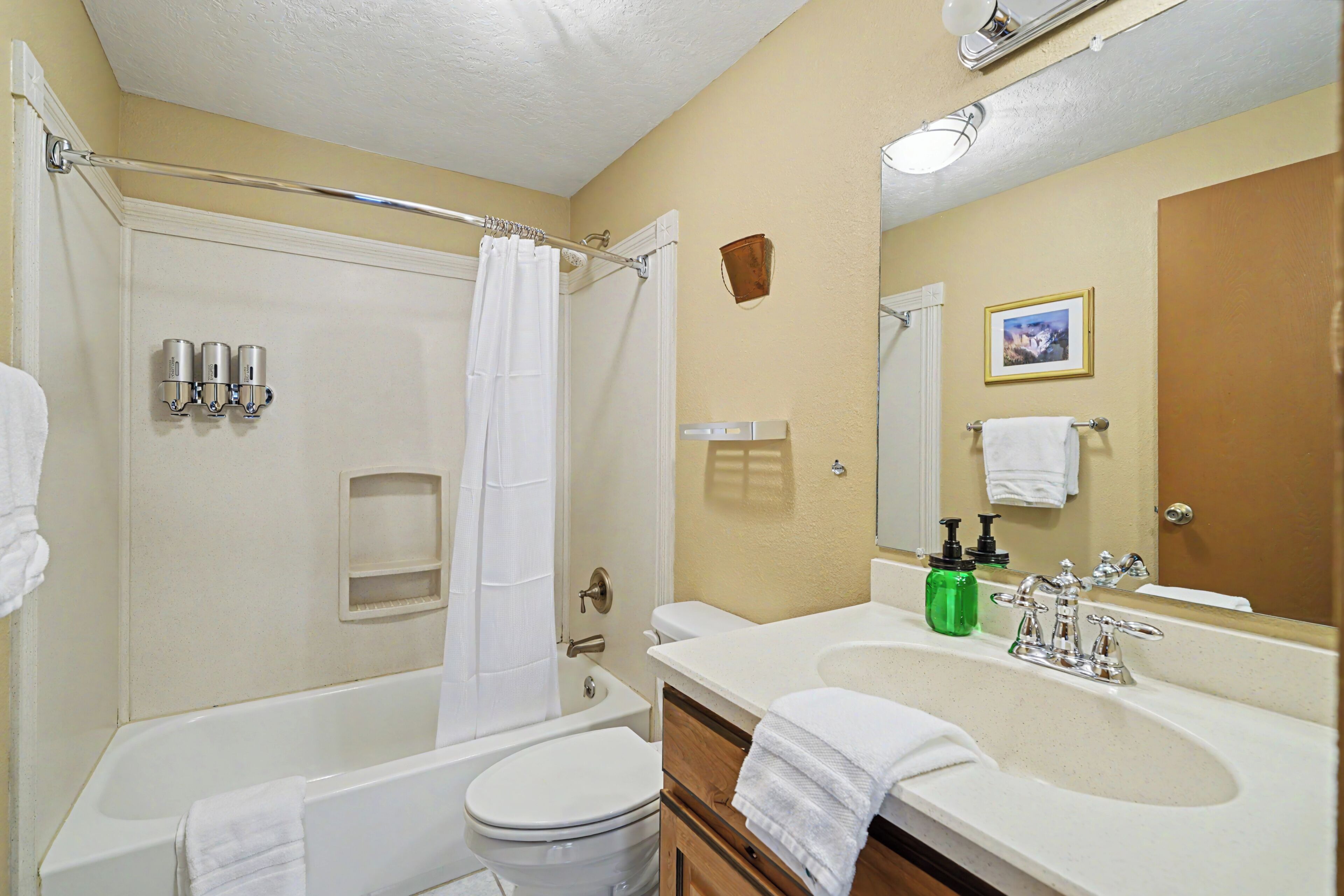 A standard hotel bathroom with a bathtub, toilet, sink, and a mirror.