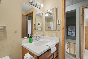 Un baño con lavamanos doble, un espejo, toallero y zona de ducha.