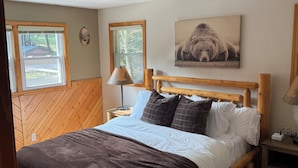 Ein hölzernes Bett mit Kopfteil, ein Nachttisch mit Lampe und ein Gemälde an der Wand.