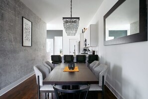 A dining room with a long table, six chairs, a chandelier, and a large mirror on the wall. - City Views In Hillsboro Village for 24 Guests, Garage, Walk to Vanderbilt And Boutique Shopping (Nashville)