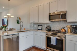 Una cocina moderna con armarios blancos, electrodomésticos de acero inoxidable y un salpicadero con diseño de espiga.
