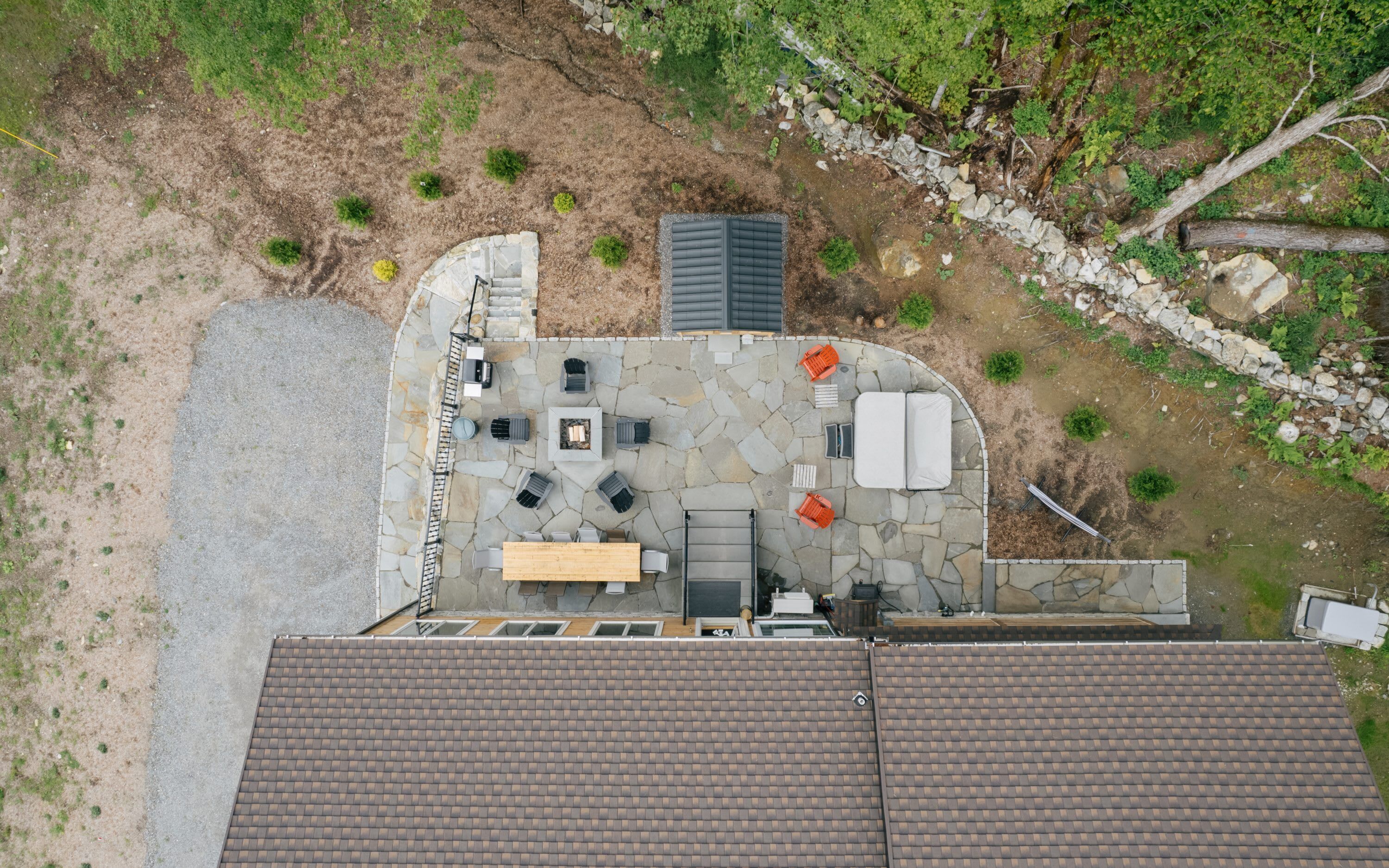 Ein Blick von oben auf eine Dachterrasse mit Steinboden, Gartenmöbeln und einem kleinen Gartenbereich.