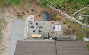 Vue aérienne d’une terrasse sur le toit, avec un sol en pierre, des meubles d’extérieur et un petit espace jardin.