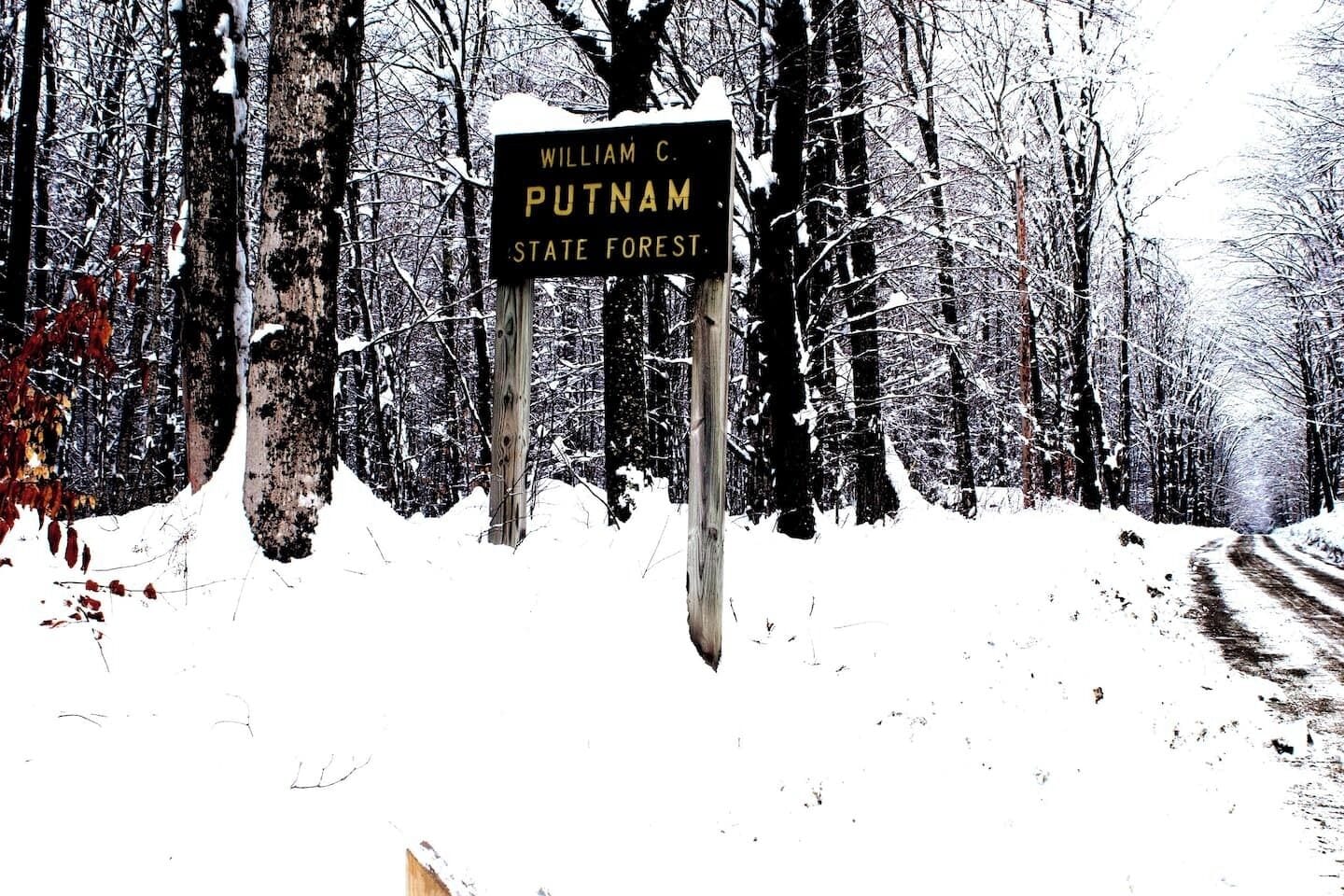 Un panneau indicateur dans une forêt enneigée, portant l’inscription « Forêt d’État William C. Putnam ».