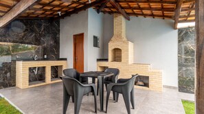 An outdoor patio with a brick fireplace, a sink, and a table with chairs. - Casa c Piscina e Churrasqueira - Nova Calif Rnia (Cabo Frio)