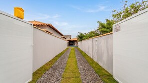 A narrow pathway with a tiled roof and a small pool in the distance. - Casa c Piscina e Churrasqueira - Nova Calif Rnia (Cabo Frio)