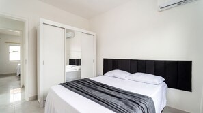 A bedroom with a bed, a wardrobe, and a wall-mounted air conditioning unit. - Casa c Piscina e Churrasqueira - Nova Calif Rnia (Cabo Frio)