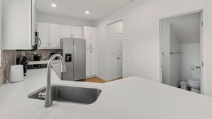 A modern kitchen with white cabinetry, a stainless steel refrigerator, and a sink. - New 3bdrHome • 2 Min to Downtown.2.5 bathroom (Spartanburg)