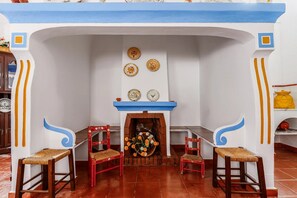 A room with a fireplace, two red chairs, and a table. There are decorative plates on the wall above the fireplace. - Country House 'Casa Da Quinta' with Shared Pool and Shared Garden (Évora)