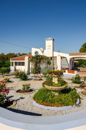 A white building with a tower, surrounded by a garden with various plants and flowers. - Country House 'Casa Da Quinta' with Shared Pool and Shared Garden (Évora)