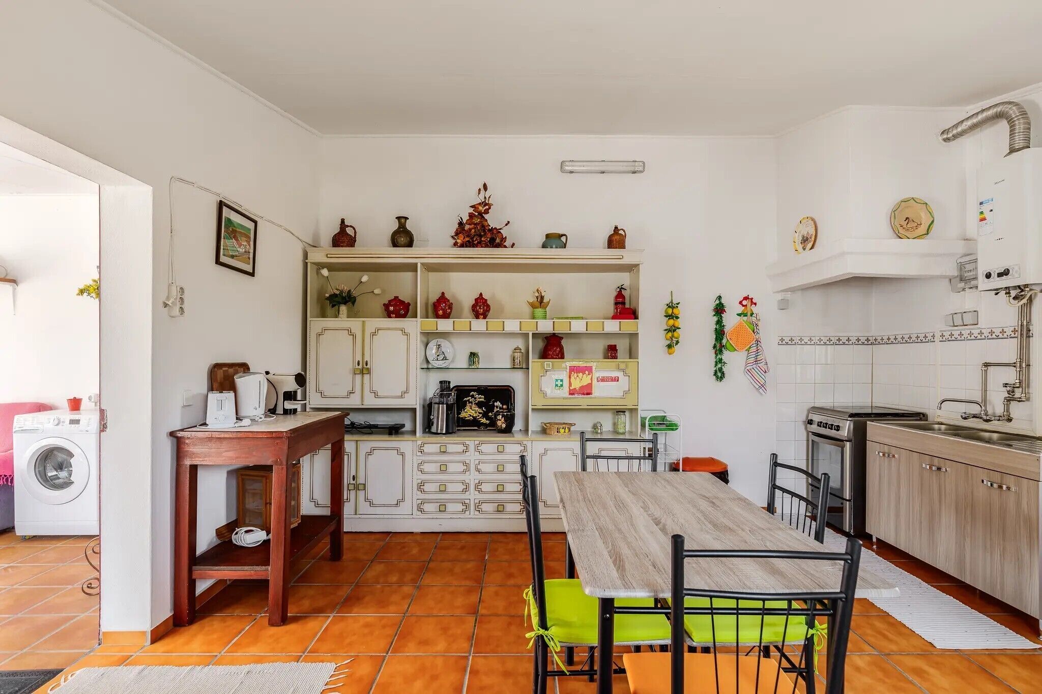 A compact kitchen with a dining area, featuring a built-in oven, a sink, and various kitchen appliances.