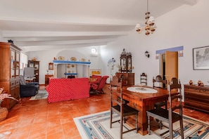 Ein geräumiges Wohnzimmer mit einem roten Sofa, einem Holzespeisetisch und einer Chandelier.