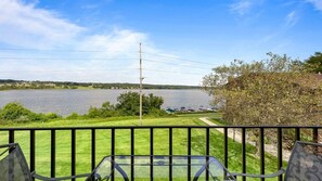Ein Balkon mit Blick auf einen See, eine Wiese und eine entfernte Uferlinie.