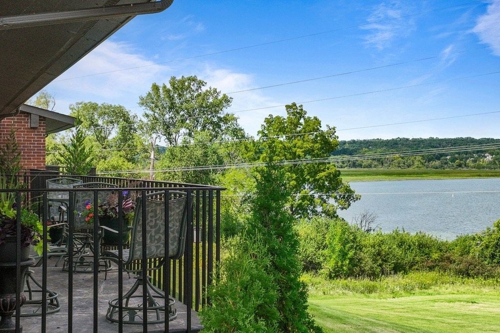 Une terrasse avec des meubles d’extérieur, une vue sur un lac et une pelouse.