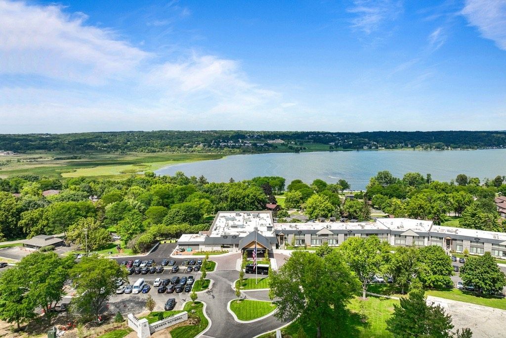 A large building with a parking lot and a lake in the background.
