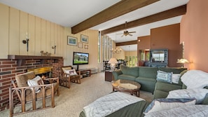 Ein Wohnzimmer mit Kamin, Fernseher, einer Couch und einem Essbereich mit Tisch und Stühlen.