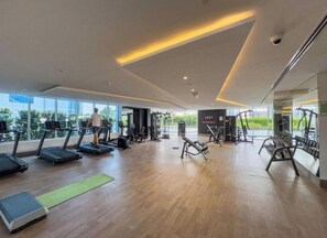 A modern gym with treadmills, weight machines, and a large window.