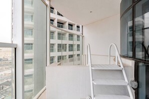 Ein modernes Gebäude mit Glasfassade, weißer Außenwand und einer Metalltreppe, die zu einer oberen Ebene führt.