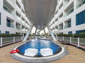 A modern indoor swimming pool with a unique architectural design, surrounded by a white fence and a poolside area.