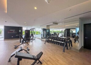 Ein modernes Fitnessstudio mit verschiedenen Trainingsgeräten, einer motivierenden Wand und großen Fenstern.