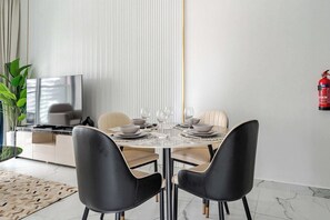 A dining area with a round table, two black chairs, and a fire extinguisher on the wall. - Luxury 2BR Dubai Retreat with Pool, Gym & Housekeeping (Dubai)