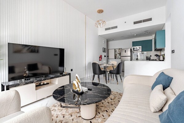 A modern living room with a flat-screen TV, a marble coffee table, and a sofa.