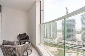 A balcony with a view of high-rise buildings and a chair.