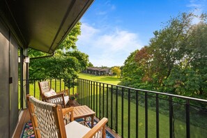 A balcony with a view of a golf course, a chair, a small table, and a railing. - Luxury Lake Geneva 2BR/2BA retreat fully renovated sleeps up to 6 near lake Como (Lake Geneva)
