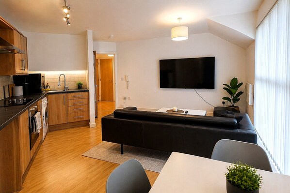 Een modern appartement met keuken, woonruimte en een flatscreen televisie aan de muur.