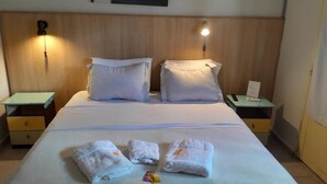 Ett hotellrum med en säng, två sängbord och en väggmonterad lampa.