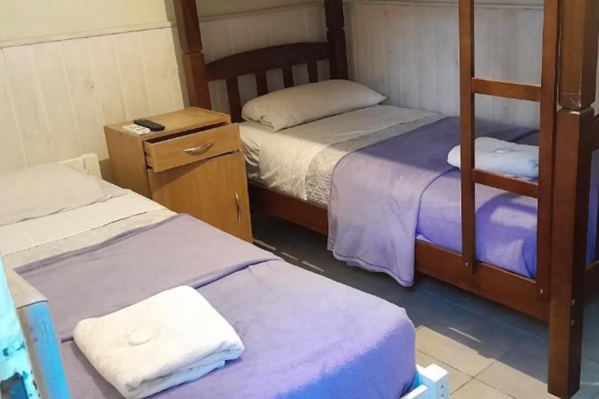 Une pièce comprenant deux lits superposés en bois, une table de chevet en bois et une petite table en bois.