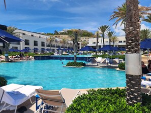 A pool area with lounge chairs and umbrellas, surrounded by palm trees and buildings. - Spacious Dawn Beach 3-bedroom condo in delightful Upper Prince's Quarter (Upper Prince's Quarter)