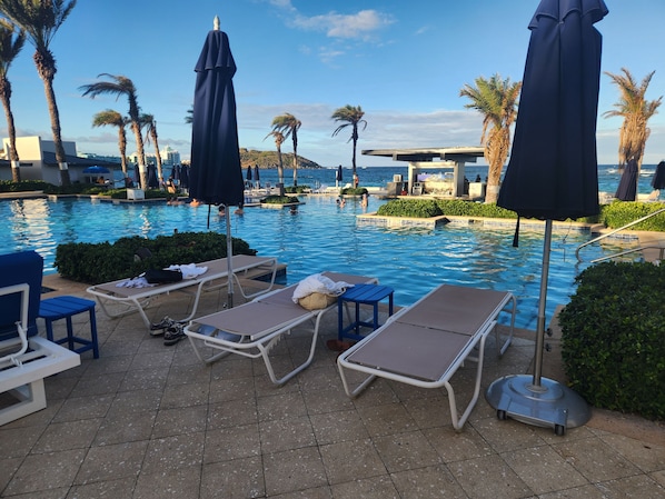A poolside area with lounge chairs and umbrellas, a tiled floor, and a view of the sea. - Spacious Dawn Beach 3-bedroom condo in delightful Upper Prince's Quarter (Upper Prince's Quarter)
