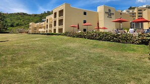 Ein Hotel mit flachem Dach, mehreren Balkonen und roten Sonnenschirmen.