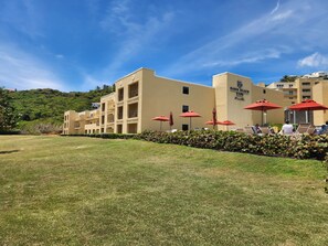 A hotel with a flat roof, multiple balconies, and red umbrellas. - Spacious Dawn Beach 3-bedroom condo in delightful Upper Prince's Quarter (Upper Prince's Quarter)