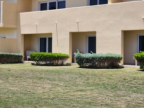 Un edificio con fachada plana, múltiples ventanas y un césped cuidado con arbustos podados.