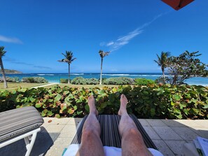 A lounge area with a view of the ocean, palm trees, and a clear sky. - Spacious Dawn Beach 3-bedroom condo in delightful Upper Prince's Quarter (Upper Prince's Quarter)