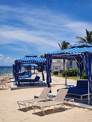 A beachside resort with sun loungers and striped canopies. - Spacious Dawn Beach 3-bedroom condo in delightful Upper Prince's Quarter (Upper Prince's Quarter)