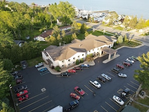 A multi-story hotel with a parking lot, surrounded by greenery and a marina. - Queen Room Escape Near Lake Huron, Beaches & Tawas City Attractions (Tawas City)