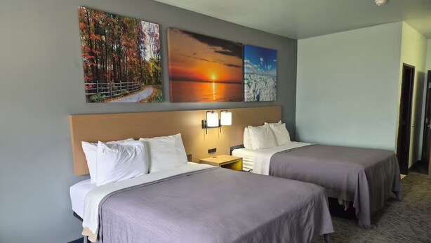 Camera d'albergo con due letti, un comodino e decorazioni murali raffiguranti paesaggi naturali.