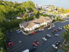 A multi-story hotel with a parking lot, surrounded by greenery and a marina. - Tawas City Two-Queen Room Near Beaches, Parks & Lake Huron (Tawas City)
