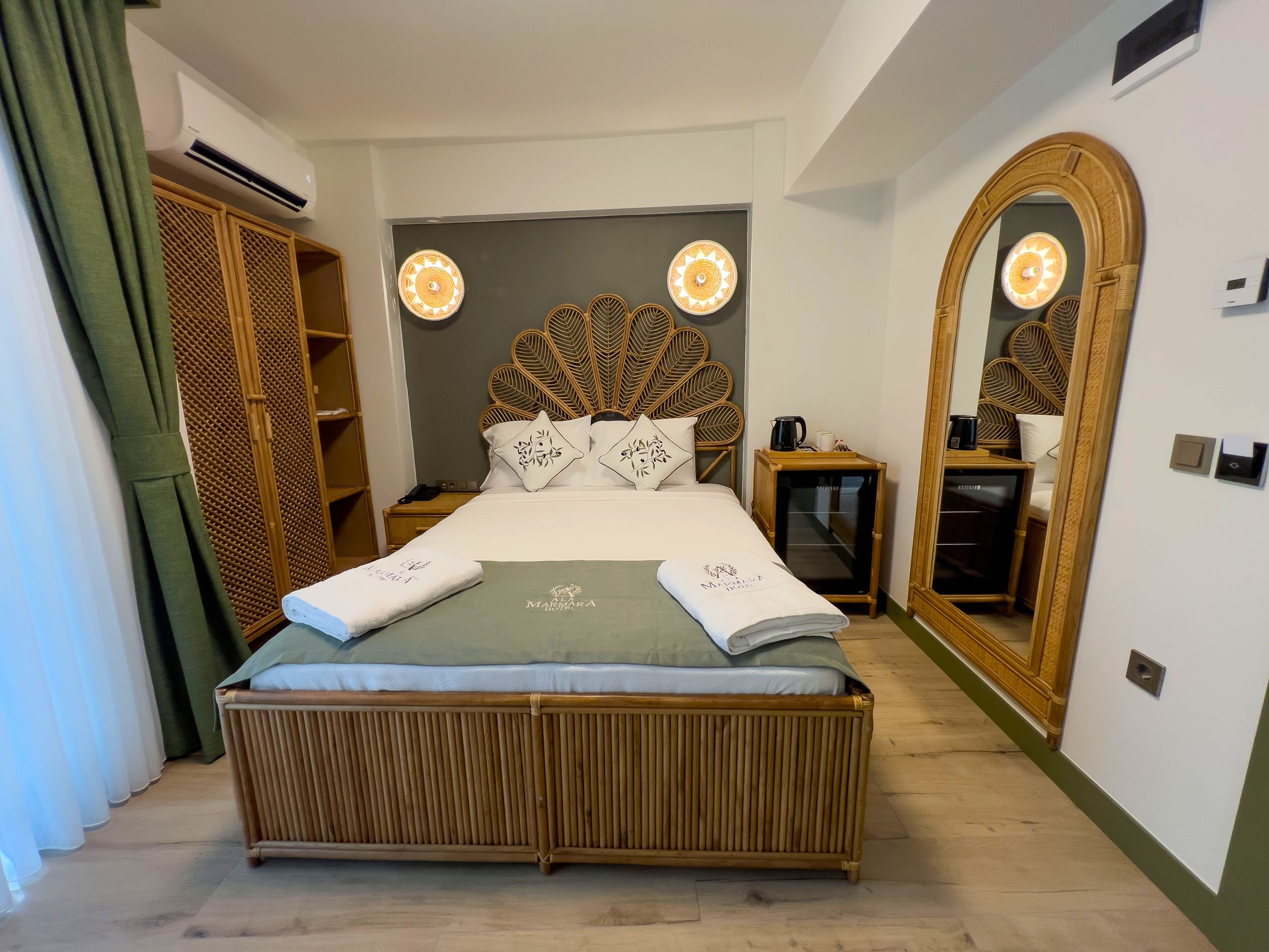 Una habitación de hotel con una cama grande, una mesita de noche, un espejo y un armario.