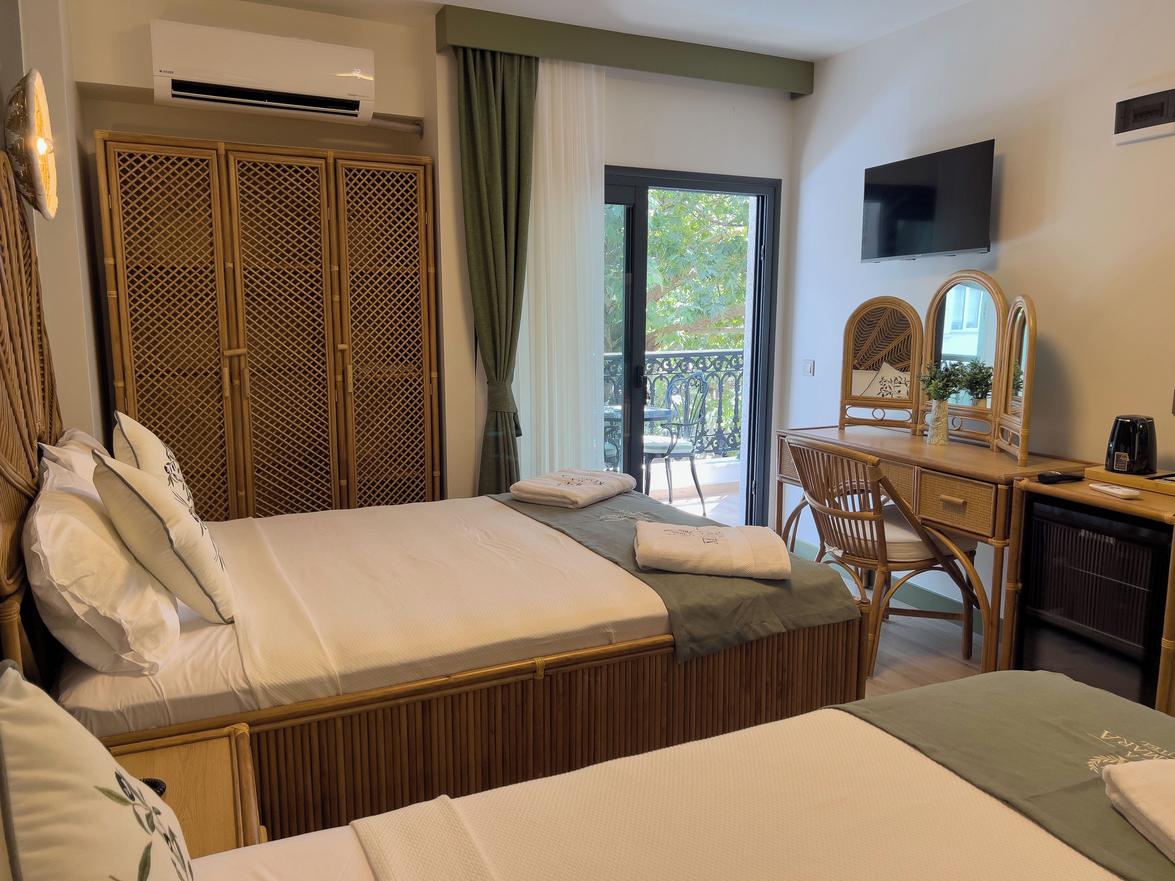 Une chambre d’hôtel comprenant un lit, un bureau, une chaise, une télévision et un balcon avec vue sur la verdure.