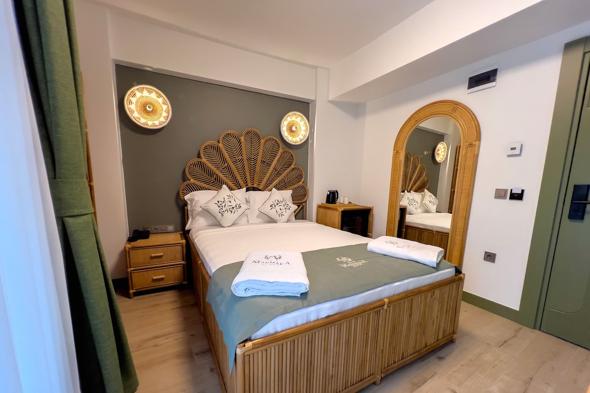 A hotel room with a large bed, a wooden headboard, a mirror, and a bedside table with a lamp.