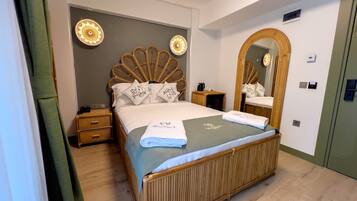 Een hotelkamer met een groot bed, een houten hoofdbord, een spiegel en een nachtkastje met een lamp.