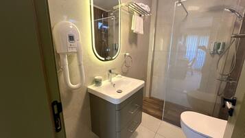 Une salle de bain moderne dotée d’une douche à parois de verre, d’un lavabo encastré et d’un meuble-lavabo avec des tiroirs.
