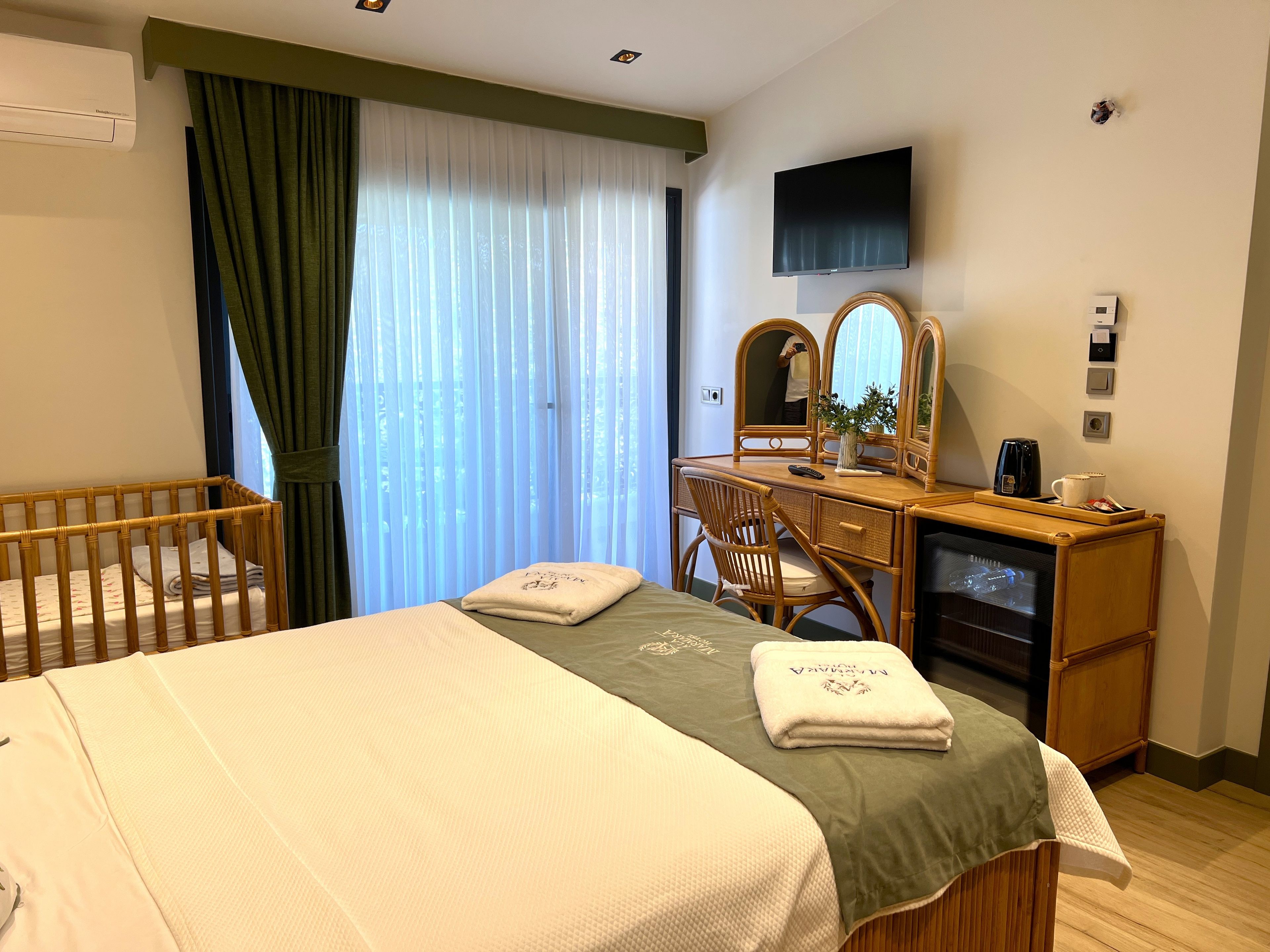 Ein Hotelzimmer mit Bett, Schreibtisch mit Stuhl, Fernseher und einem Fenster mit Vorhängen.